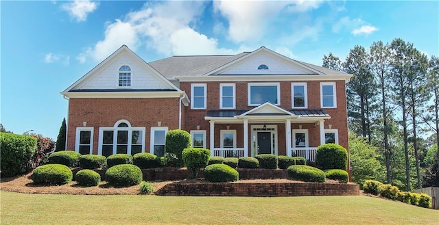 view of front of house with brick siding, covered porch, and a front yard