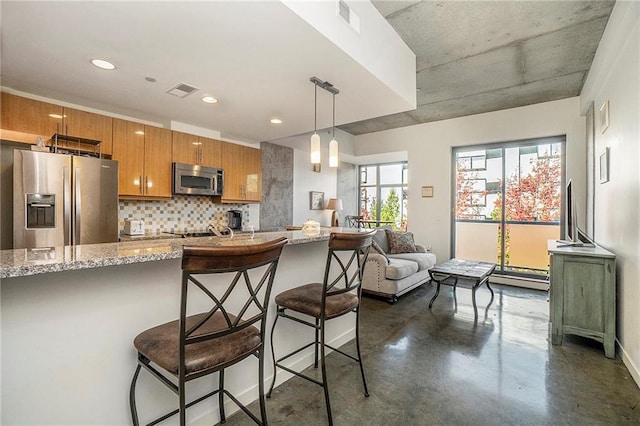 kitchen with a kitchen breakfast bar, stainless steel appliances, light stone countertops, pendant lighting, and tasteful backsplash