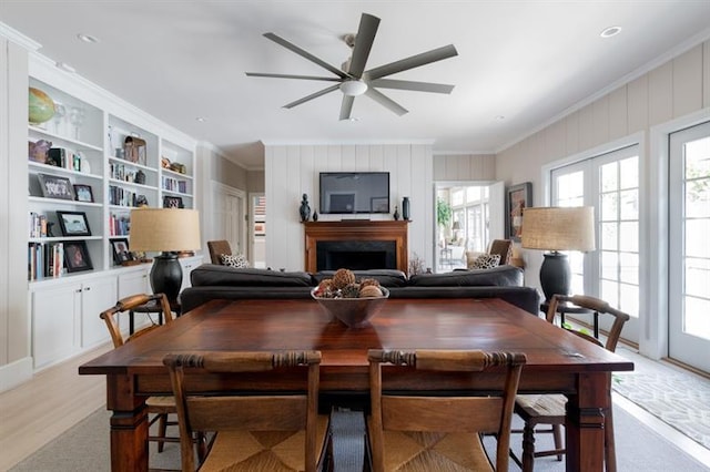 dining space with light wood-style flooring, ornamental molding, a fireplace, and ceiling fan