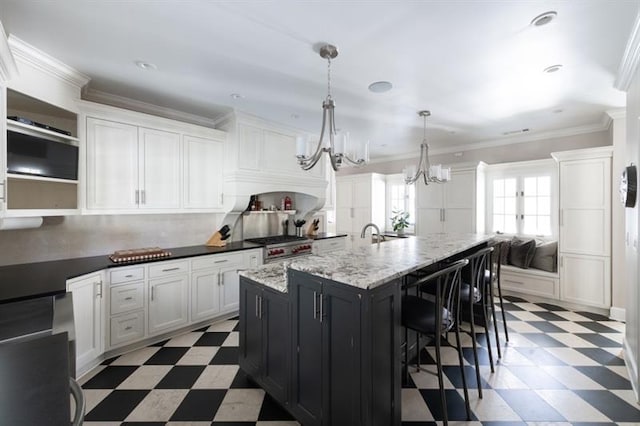 kitchen with a kitchen bar, ornamental molding, dark cabinetry, light floors, and a chandelier