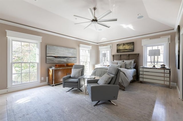 bedroom featuring a raised ceiling, vaulted ceiling, light wood finished floors, and ornamental molding