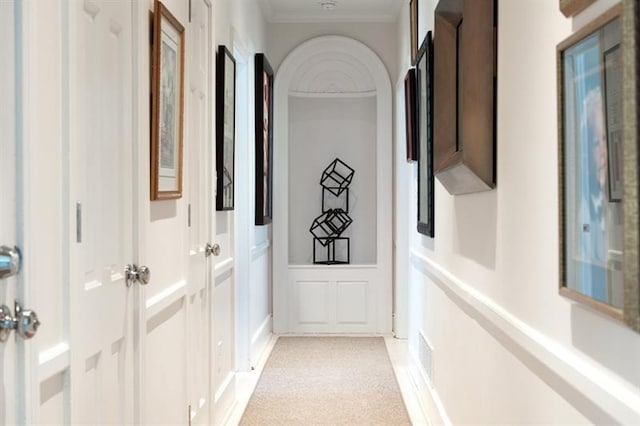 corridor featuring light colored carpet and crown molding