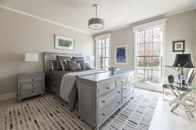 bedroom with light wood-style flooring, crown molding, and baseboards