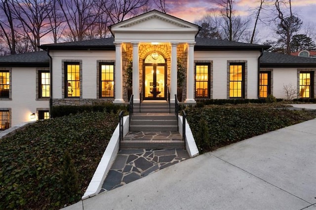 greek revival house with stone siding and french doors