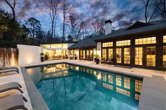 pool with french doors and a patio area