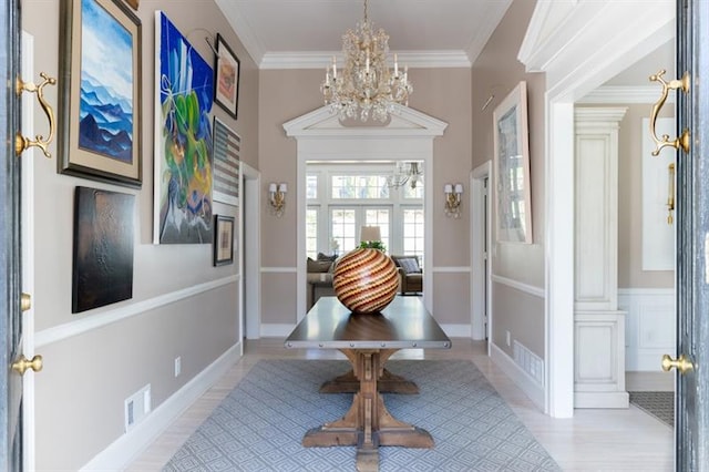 foyer entrance with visible vents, a notable chandelier, crown molding, and light wood finished floors