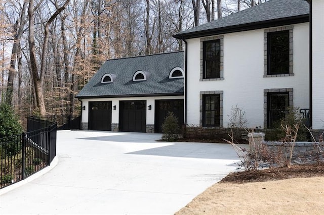 view of front of property with a garage, fence, concrete driveway, and a shingled roof