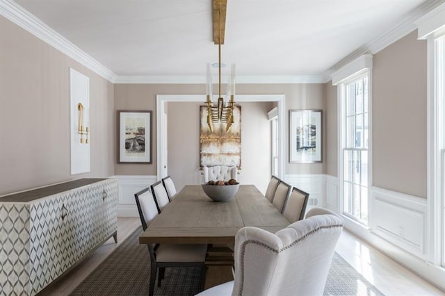 dining room featuring crown molding, a decorative wall, and wainscoting