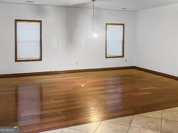 empty room featuring baseboards, a notable chandelier, and wood finished floors