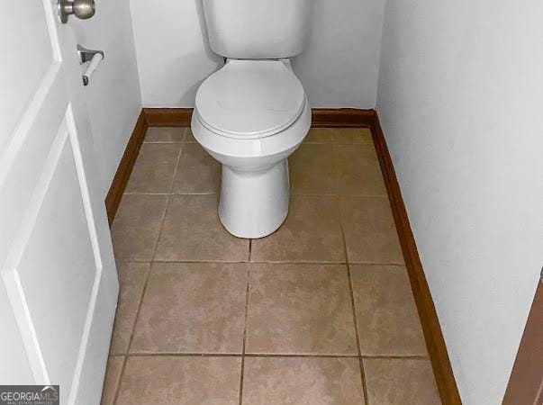 bathroom with baseboards, toilet, and tile patterned flooring