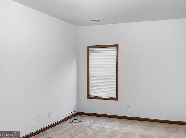 empty room with visible vents, light carpet, and baseboards