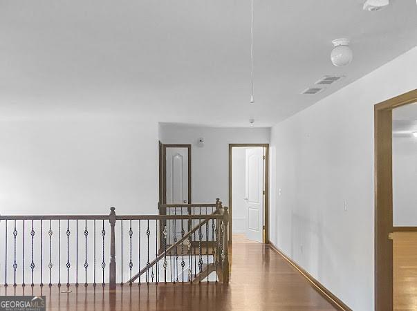 corridor with wood finished floors, attic access, an upstairs landing, and visible vents