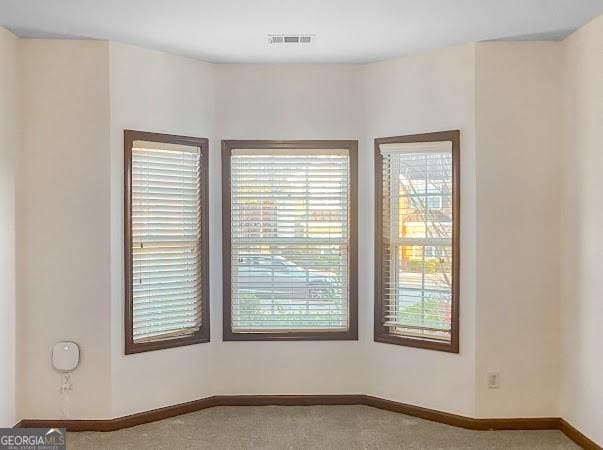 carpeted empty room featuring visible vents and baseboards