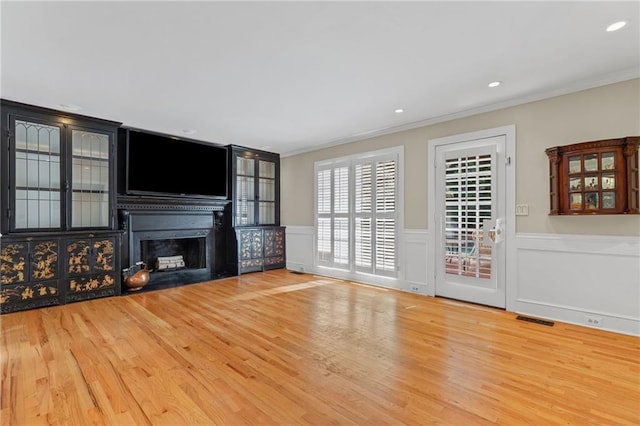 3231 Connemara Trce, Lawrenceville, GA 30044 - unfurnished living room featuring wood finished floors, crown molding, a fireplace with flush hearth, wainscoting, and recessed lighting