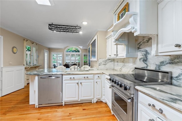 3231 Connemara Trce, Lawrenceville, GA 30044 - kitchen with appliances with stainless steel finishes, a peninsula, white cabinets, light wood-style flooring, and ornamental molding