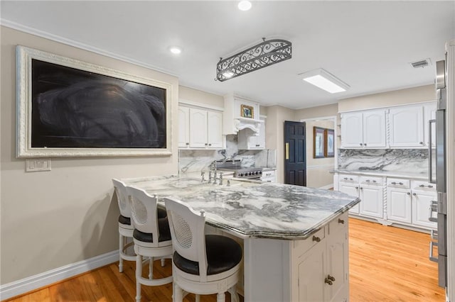 3231 Connemara Trce, Lawrenceville, GA 30044 - kitchen with white cabinets, decorative backsplash, a peninsula, light wood finished floors, and a kitchen breakfast bar