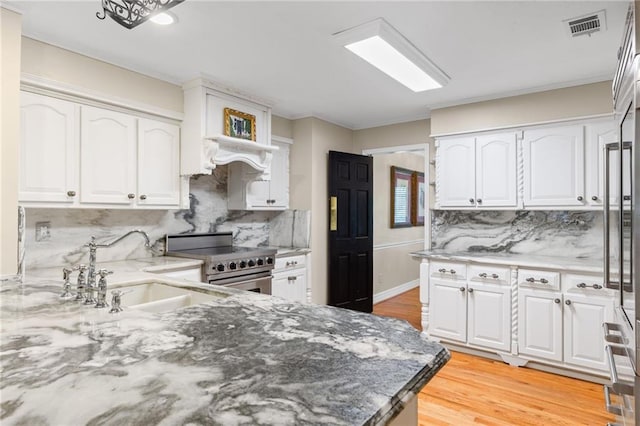 3231 Connemara Trce, Lawrenceville, GA 30044 - kitchen featuring stainless steel electric stove, a sink, light stone counters, decorative backsplash, and light wood finished floors