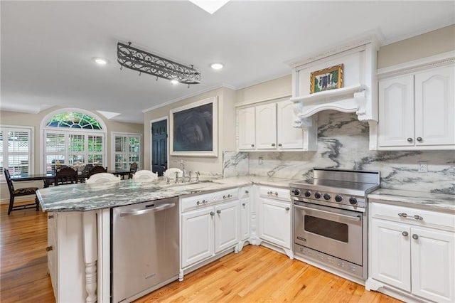 3231 Connemara Trce, Lawrenceville, GA 30044 - kitchen featuring stainless steel appliances, a peninsula, light wood-style floors, light stone counters, and crown molding