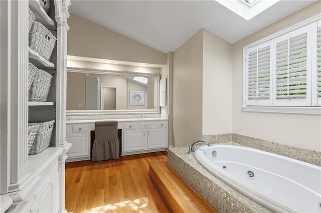 3231 Connemara Trce, Lawrenceville, GA 30044 - full bathroom with vanity, a jetted tub, a skylight, wood finished floors, and vaulted ceiling