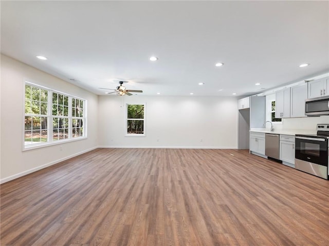 unfurnished living room with light wood-style flooring, baseboards, and recessed lighting