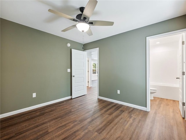 unfurnished bedroom featuring ensuite bathroom, wood finished floors, and baseboards