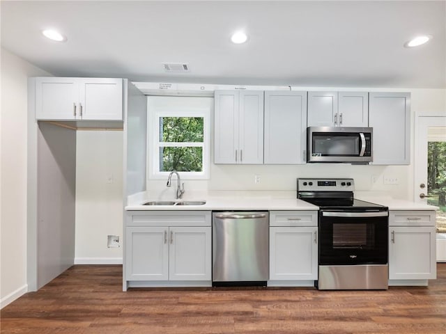 kitchen with wood finished floors, light countertops, stainless steel appliances, a sink, and recessed lighting