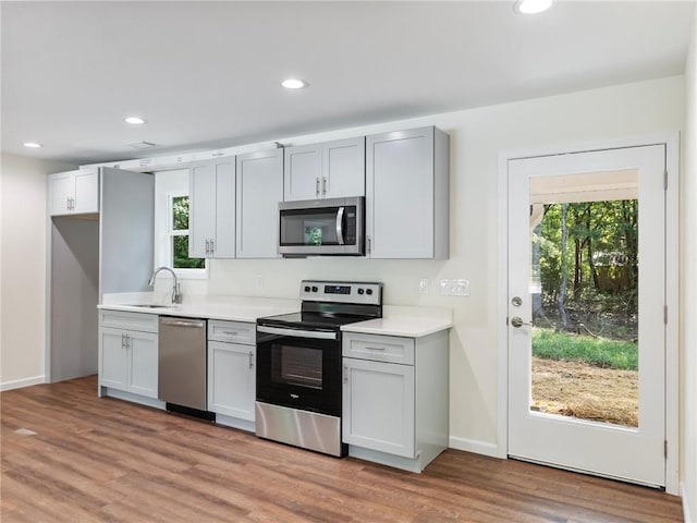 kitchen featuring recessed lighting, stainless steel appliances, a sink, light wood-style floors, and light countertops