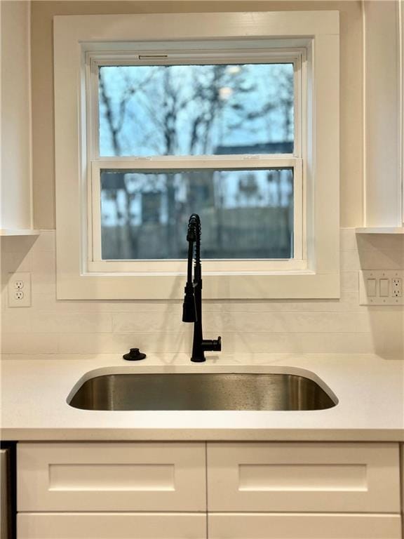 interior details with sink, decorative backsplash, and white cabinets