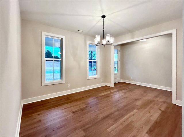 unfurnished dining area with dark hardwood / wood-style flooring and a notable chandelier