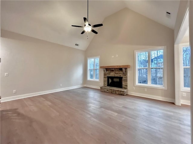 unfurnished living room with ceiling fan, high vaulted ceiling, a stone fireplace, and hardwood / wood-style floors