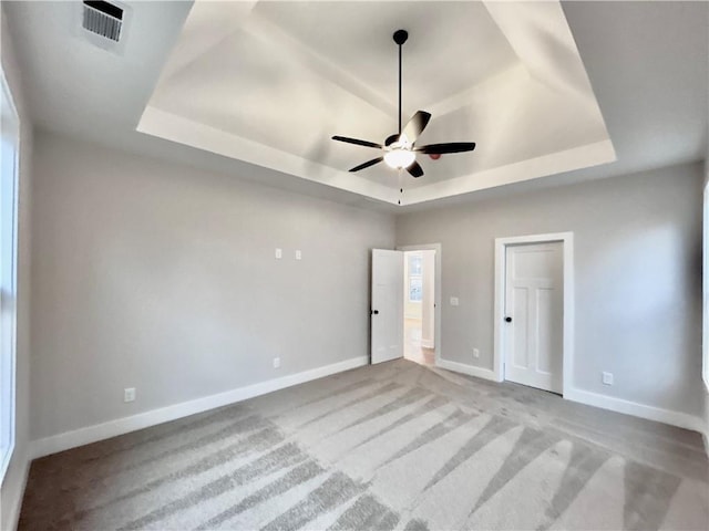 unfurnished bedroom featuring light carpet, ceiling fan, and a tray ceiling