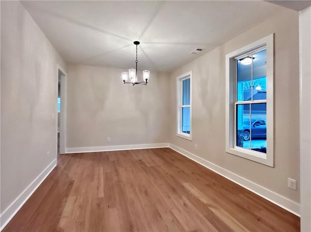 unfurnished dining area with hardwood / wood-style flooring and a chandelier