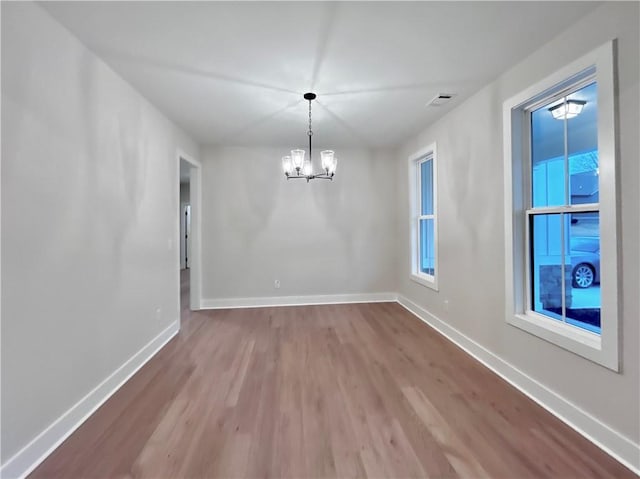 spare room featuring an inviting chandelier and wood-type flooring