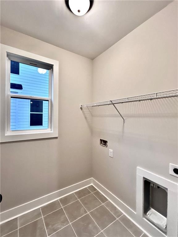 washroom with dark tile patterned flooring and electric dryer hookup