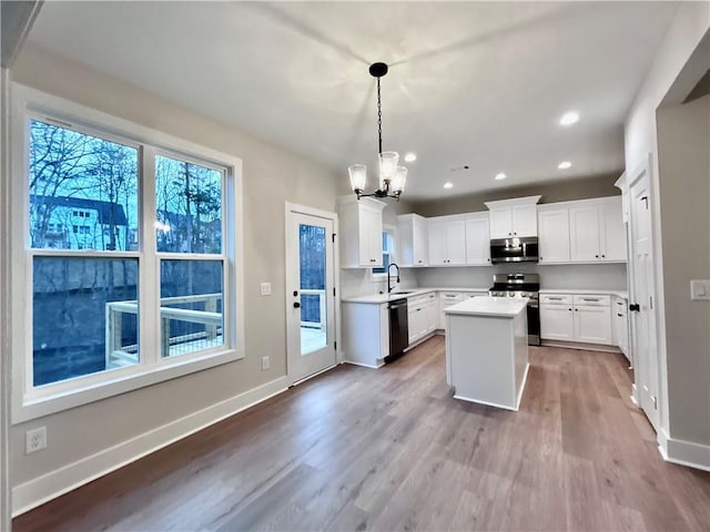 kitchen featuring appliances with stainless steel finishes, decorative light fixtures, sink, white cabinets, and a center island