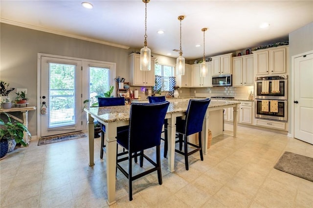 345 Piedmont Cir, Covington, GA 30016 - kitchen with stainless steel appliances, light stone countertops, a breakfast bar, pendant lighting, and crown molding