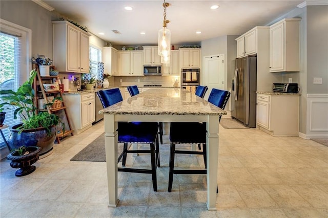 345 Piedmont Cir, Covington, GA 30016 - kitchen featuring stainless steel appliances, a center island, light stone countertops, ornamental molding, and recessed lighting