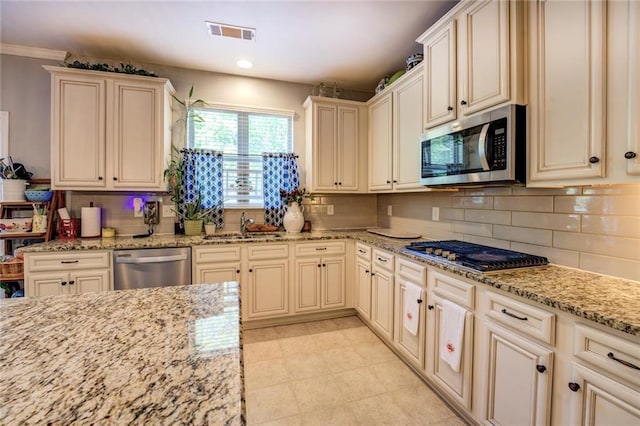 345 Piedmont Cir, Covington, GA 30016 - kitchen featuring stainless steel appliances, cream cabinets, a sink, tasteful backsplash, and light stone countertops