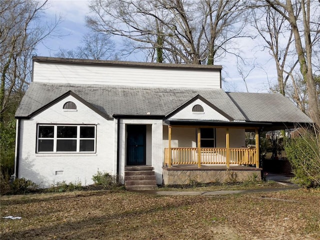 view of front facade with a porch, crawl space, brick siding, and roof with shingles