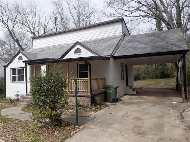 view of front facade with covered porch, a carport, a shingled roof, and concrete driveway