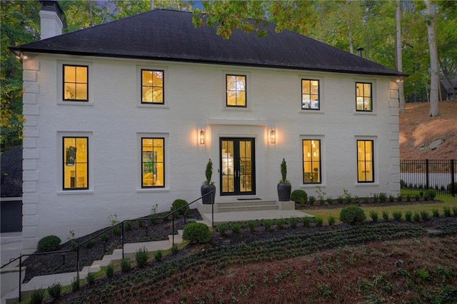 back of house with french doors, brick siding, a chimney, and fence