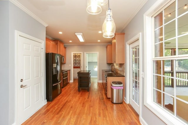 kitchen featuring sink, hanging light fixtures, a center island, crown molding, and black fridge