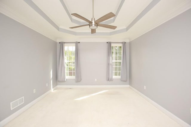 carpeted empty room with crown molding, ceiling fan, and a raised ceiling