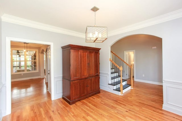 empty room with an inviting chandelier, ornamental molding, and light hardwood / wood-style floors