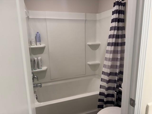 bathroom with shower / tub combo with curtain and toilet