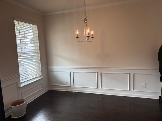 unfurnished dining area with dark wood-type flooring, ornamental molding, and a chandelier