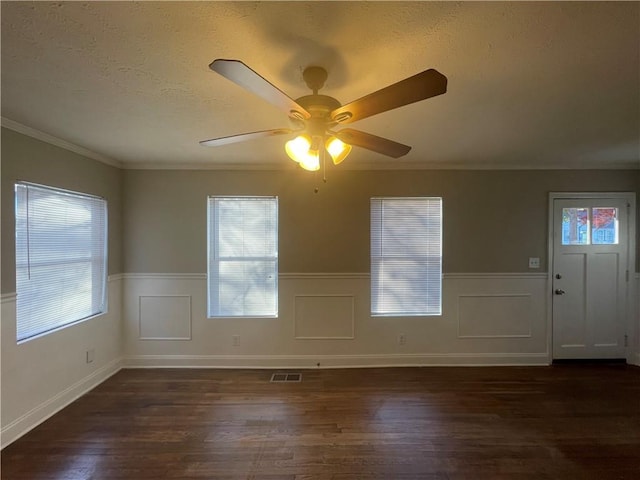 spare room featuring a textured ceiling, ceiling fan, ornamental molding, and dark wood-type flooring