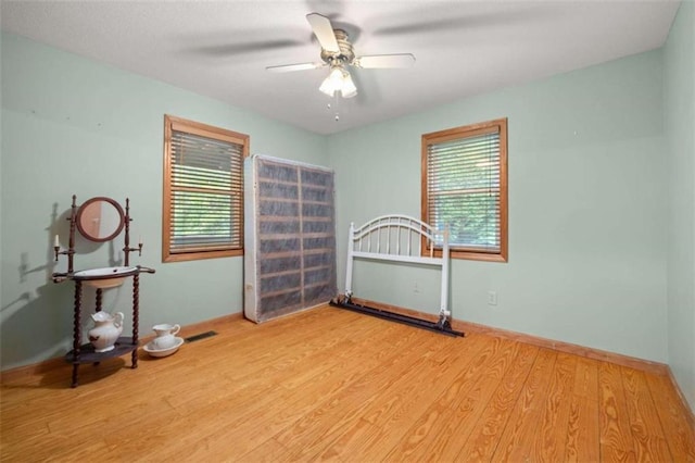 unfurnished bedroom featuring light hardwood / wood-style flooring, multiple windows, and ceiling fan