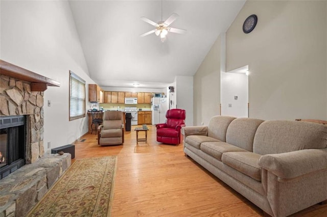 living room featuring light wood-type flooring, high vaulted ceiling, a stone fireplace, and ceiling fan