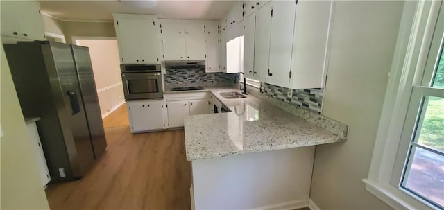 kitchen featuring light wood-type flooring, a sink, white cabinetry, appliances with stainless steel finishes, and decorative backsplash